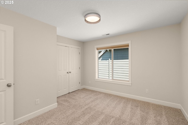 unfurnished bedroom with carpet flooring, visible vents, and baseboards