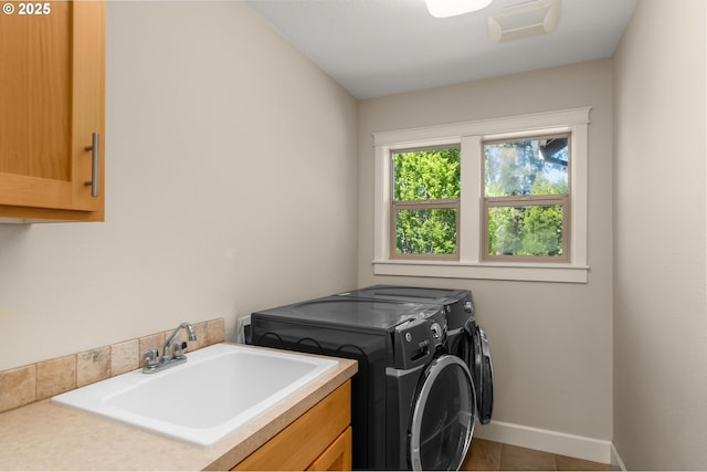 clothes washing area featuring a sink, cabinet space, washer and clothes dryer, baseboards, and tile patterned flooring