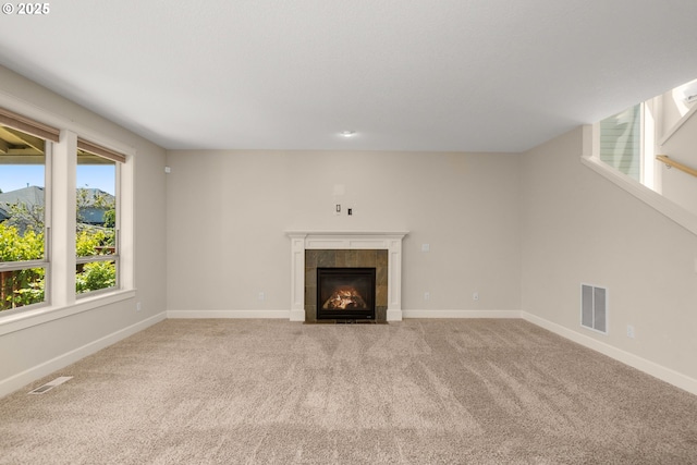 unfurnished living room with carpet, visible vents, and a tile fireplace