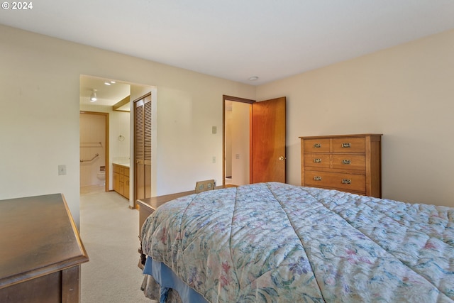 bedroom with a closet, light carpet, and connected bathroom