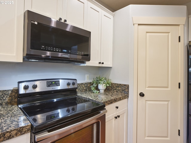 kitchen with white cabinets, dark stone counters, and appliances with stainless steel finishes