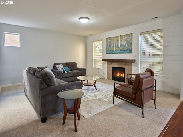 living room with a textured ceiling, a fireplace, light wood-type flooring, and a healthy amount of sunlight