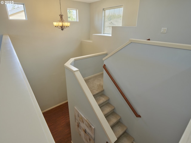 stairway with a notable chandelier and hardwood / wood-style flooring