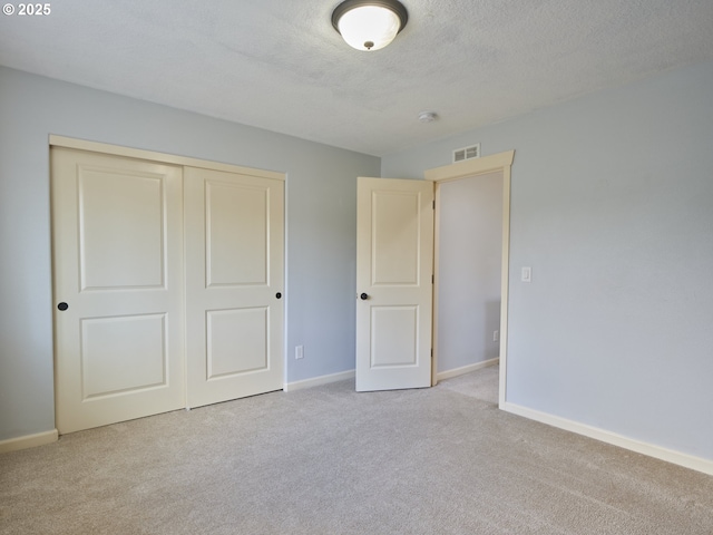 unfurnished bedroom with a textured ceiling, a closet, and light carpet