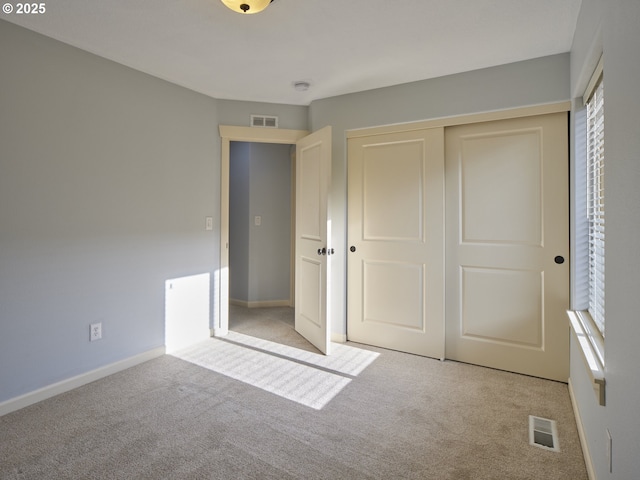 unfurnished bedroom with a closet and light colored carpet