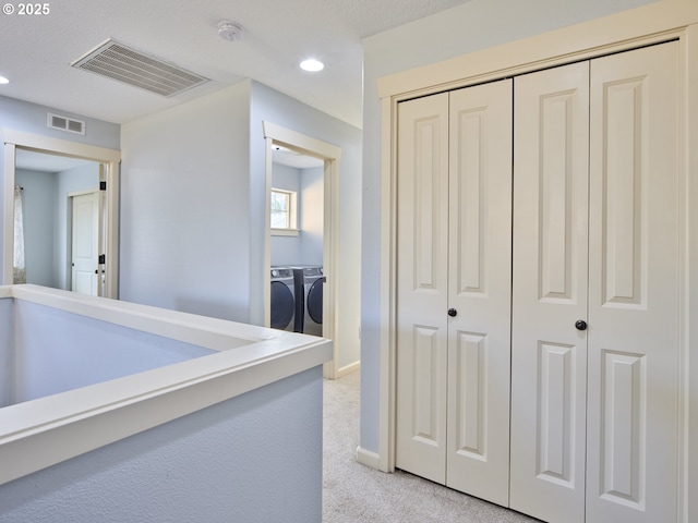 hall with separate washer and dryer and light carpet