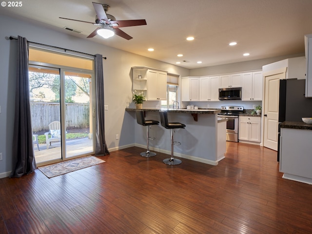 kitchen with stainless steel appliances, kitchen peninsula, ceiling fan, dark hardwood / wood-style flooring, and white cabinets