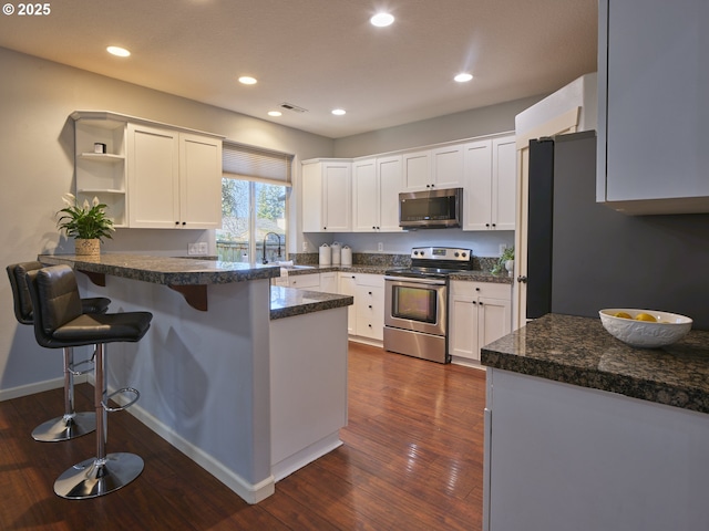 kitchen with a kitchen bar, white cabinetry, kitchen peninsula, and appliances with stainless steel finishes