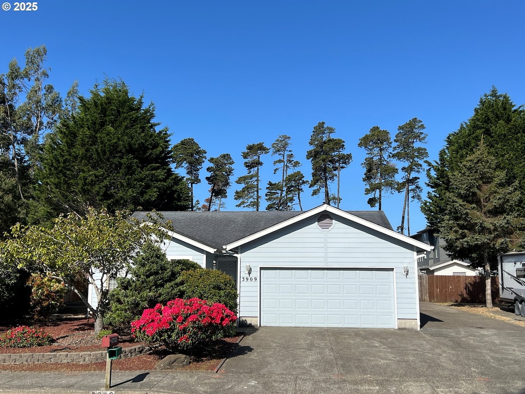 view of front of house with an attached garage, driveway, and fence