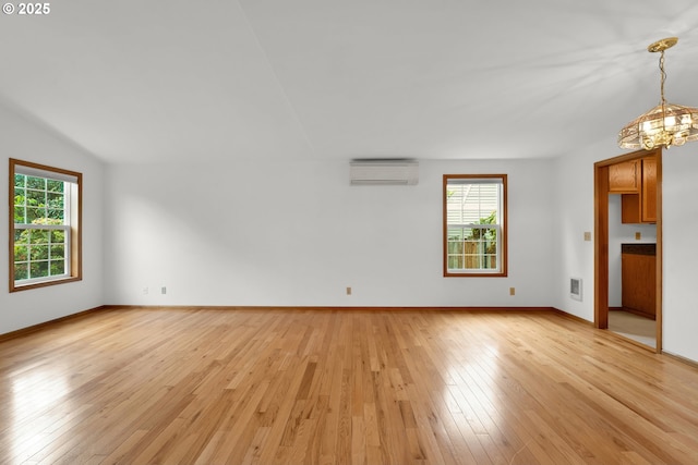 3909 Spruce St, Florence, OR 97439 - unfurnished room featuring a wall mounted AC, light wood-style floors, a chandelier, baseboards, and lofted ceiling