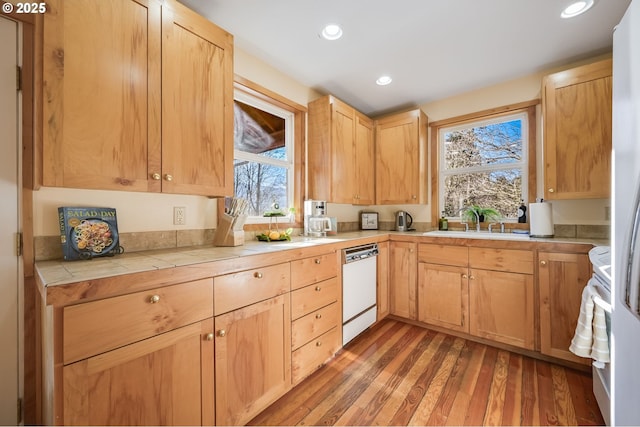 kitchen featuring hardwood / wood-style flooring, tile countertops, dishwasher, and light brown cabinets