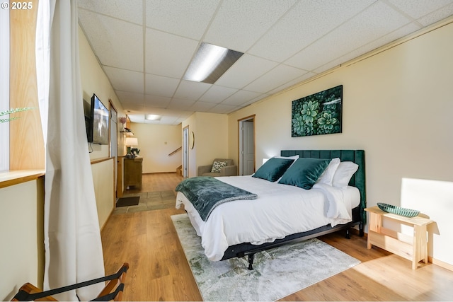 bedroom featuring light hardwood / wood-style flooring and a drop ceiling