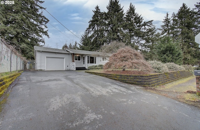 ranch-style home with a garage, aphalt driveway, and fence