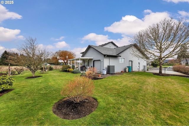 exterior space with fence, an attached garage, a yard, central AC, and a shingled roof