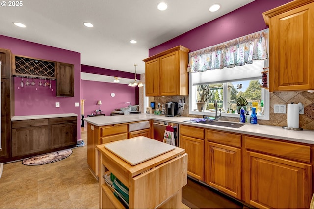 kitchen with recessed lighting, a peninsula, stainless steel dishwasher, and a sink