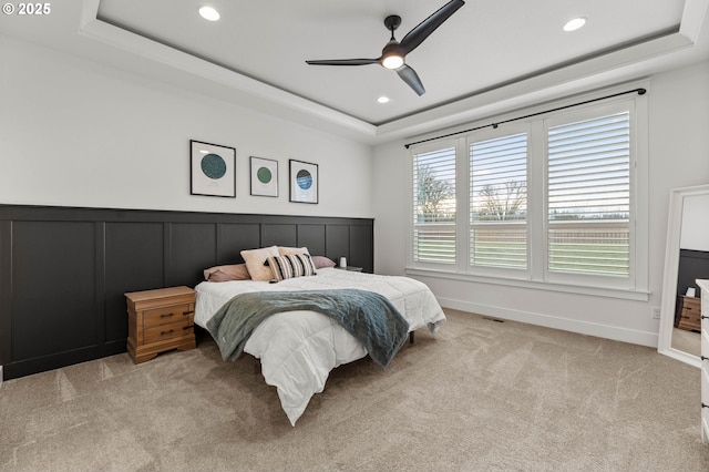 carpeted bedroom featuring ceiling fan and a tray ceiling