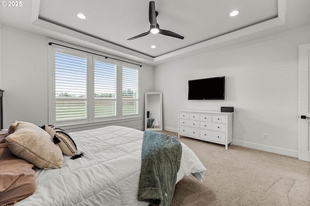 bedroom with ceiling fan, light colored carpet, and a raised ceiling