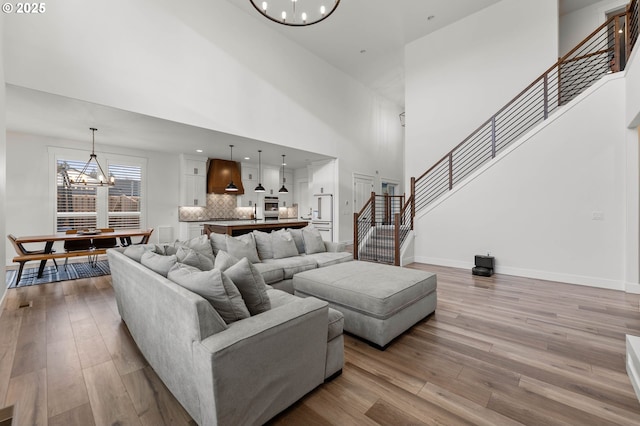 living room featuring a notable chandelier, a towering ceiling, and light hardwood / wood-style floors