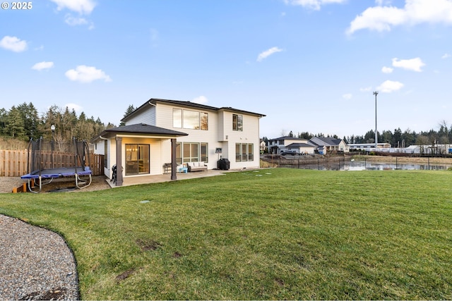 back of property with a patio, a water view, a yard, and a trampoline