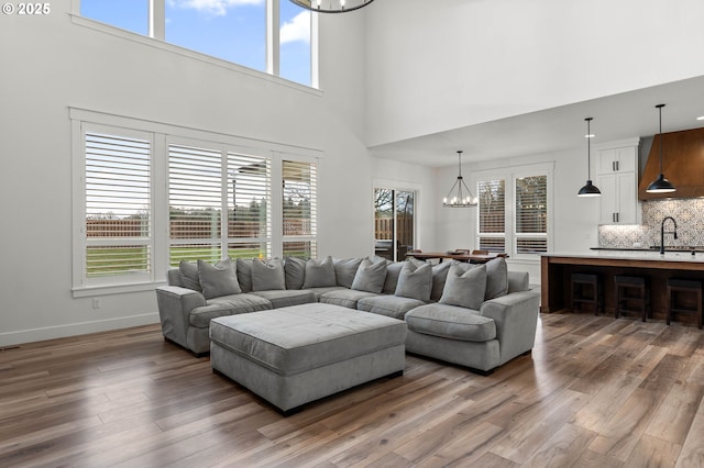 living room featuring hardwood / wood-style flooring, sink, a high ceiling, and a notable chandelier