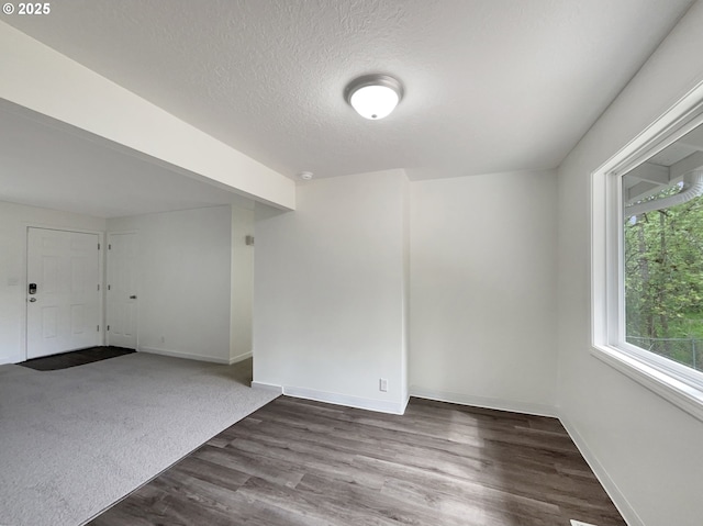 empty room featuring dark wood-type flooring, a textured ceiling, and baseboards
