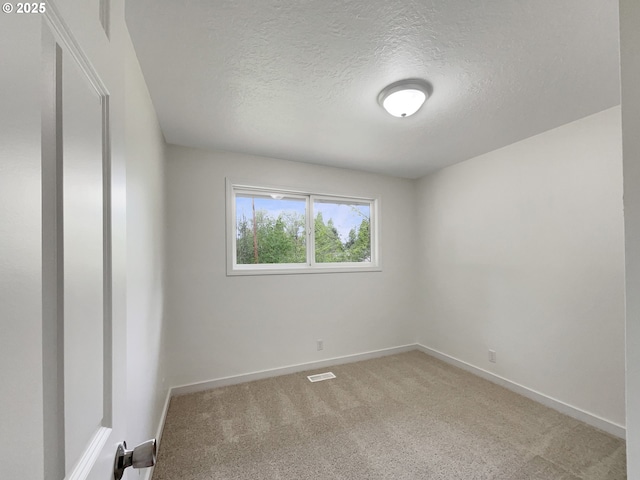 spare room featuring visible vents, a textured ceiling, baseboards, and light carpet