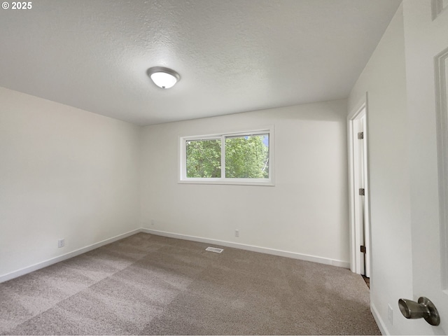 empty room with baseboards, carpet flooring, a textured ceiling, and visible vents