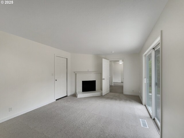 unfurnished living room featuring visible vents, baseboards, a fireplace, and light carpet