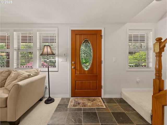 25210 E Arrah Wanna Blvd, Welches, OR 97067 - foyer entrance with baseboards, plenty of natural light, a textured ceiling, and dark stone finish flooring