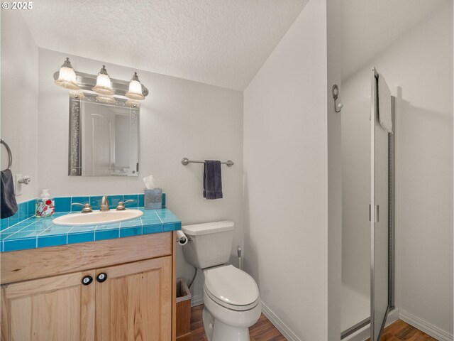 25210 E Arrah Wanna Blvd, Welches, OR 97067 - full bath with wood finished floors, vanity, toilet, a textured ceiling, and baseboards