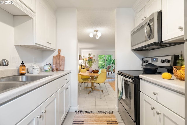 12620 NW Barnes Rd, Portland, OR 97229 - kitchen with appliances with stainless steel finishes, light tile patterned floors, white cabinetry, and light countertops