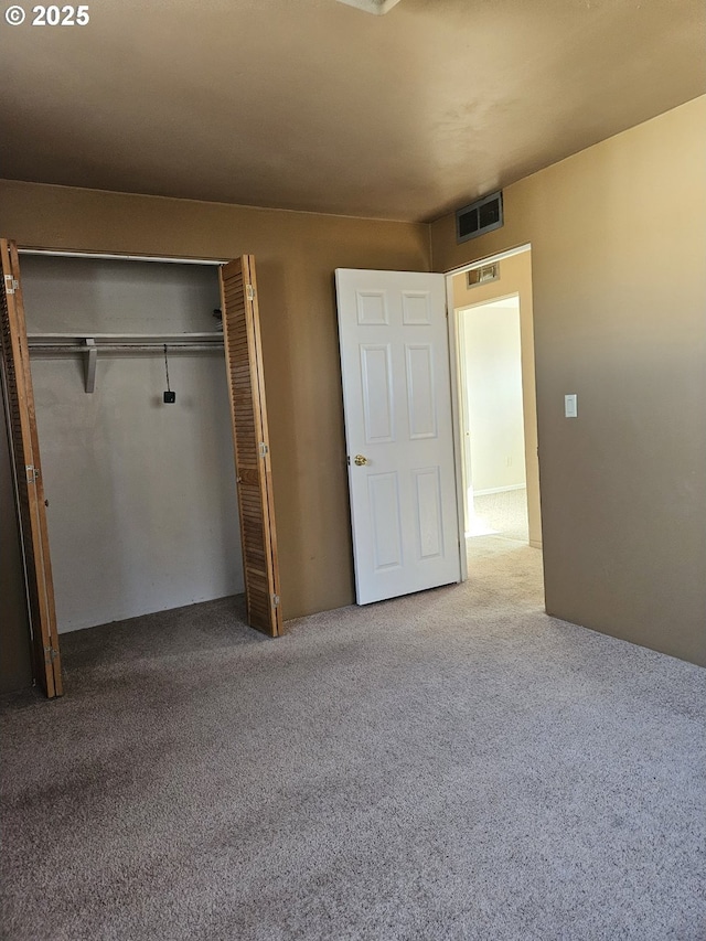 unfurnished bedroom with carpet floors, visible vents, and a closet