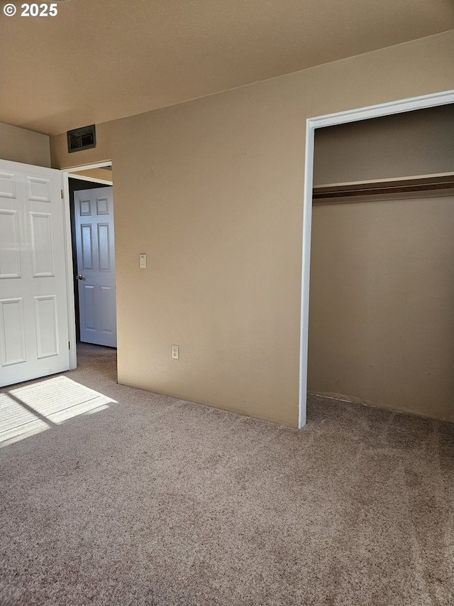 unfurnished bedroom featuring a closet, carpet flooring, and visible vents