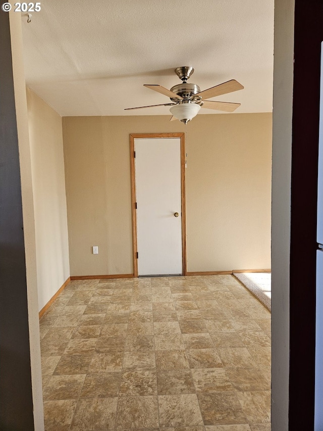 unfurnished room with ceiling fan, a textured ceiling, and baseboards