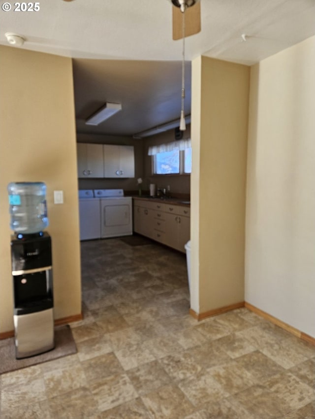 kitchen with separate washer and dryer, dark countertops, a sink, and baseboards