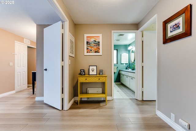 hall featuring light wood-type flooring and baseboards
