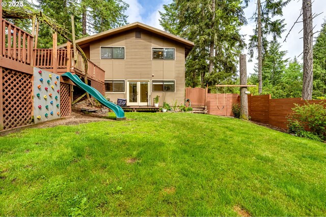 rear view of property featuring a playground and a wooden deck
