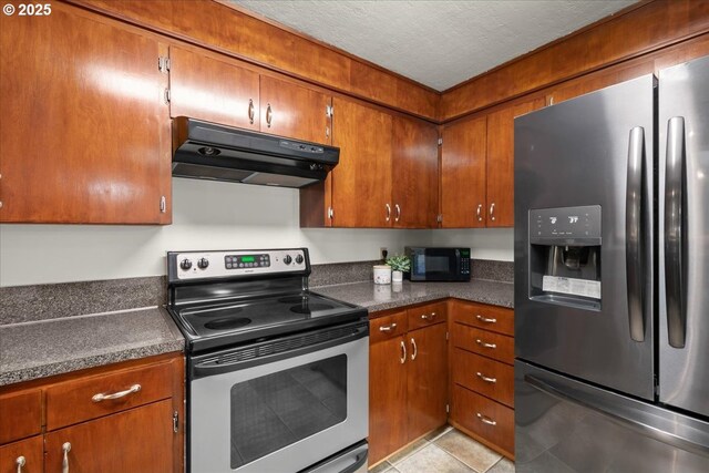 1209 NW 53rd St, Vancouver, WA 98663 - kitchen with stainless steel appliances, under cabinet range hood, dark countertops, brown cabinetry, and a textured ceiling