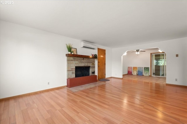 1209 NW 53rd St, Vancouver, WA 98663 - unfurnished living room with arched walkways, light wood finished floors, a wall unit AC, and a fireplace