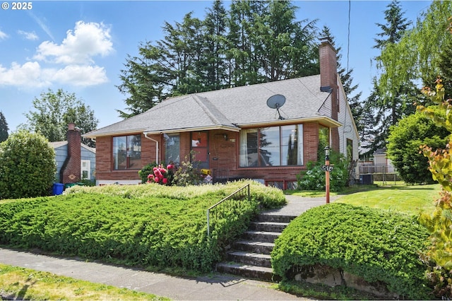 bungalow with brick siding, a chimney, fence, and central AC