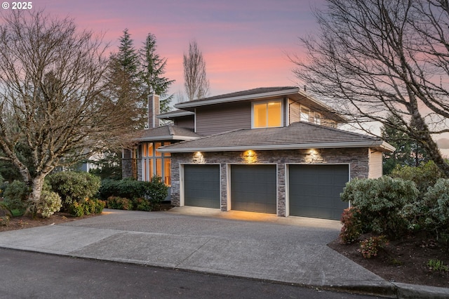 view of front of home with a garage, stone siding, driveway, and a chimney