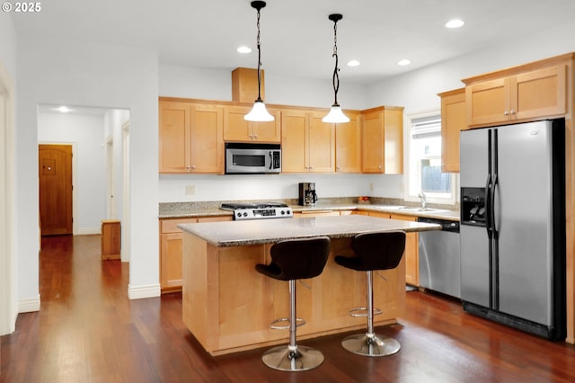 kitchen with light brown cabinetry, appliances with stainless steel finishes, a kitchen island, and dark wood-type flooring