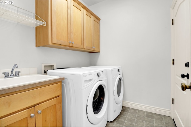 clothes washing area with separate washer and dryer, a sink, cabinet space, and baseboards