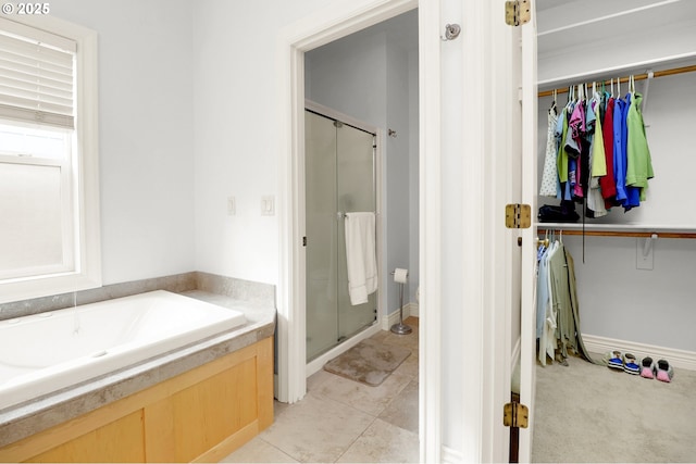 bathroom featuring a walk in closet, a shower stall, and a garden tub