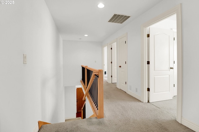 corridor with visible vents, carpet floors, baseboards, an upstairs landing, and recessed lighting
