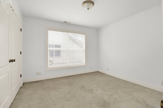 carpeted spare room featuring baseboards and visible vents
