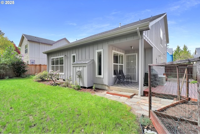 back of property featuring a lawn, board and batten siding, and fence