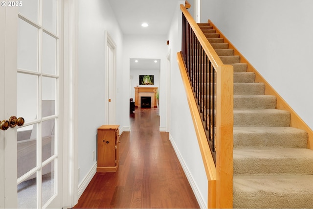 stairway featuring baseboards, a fireplace, recessed lighting, and wood finished floors