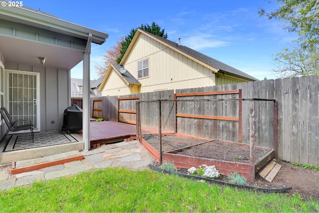 exterior space with a deck, a fenced backyard, and a vegetable garden
