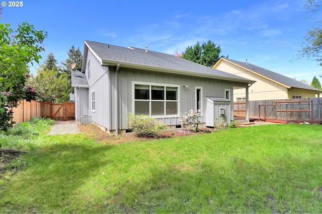 back of house with a lawn, board and batten siding, a fenced backyard, and roof with shingles